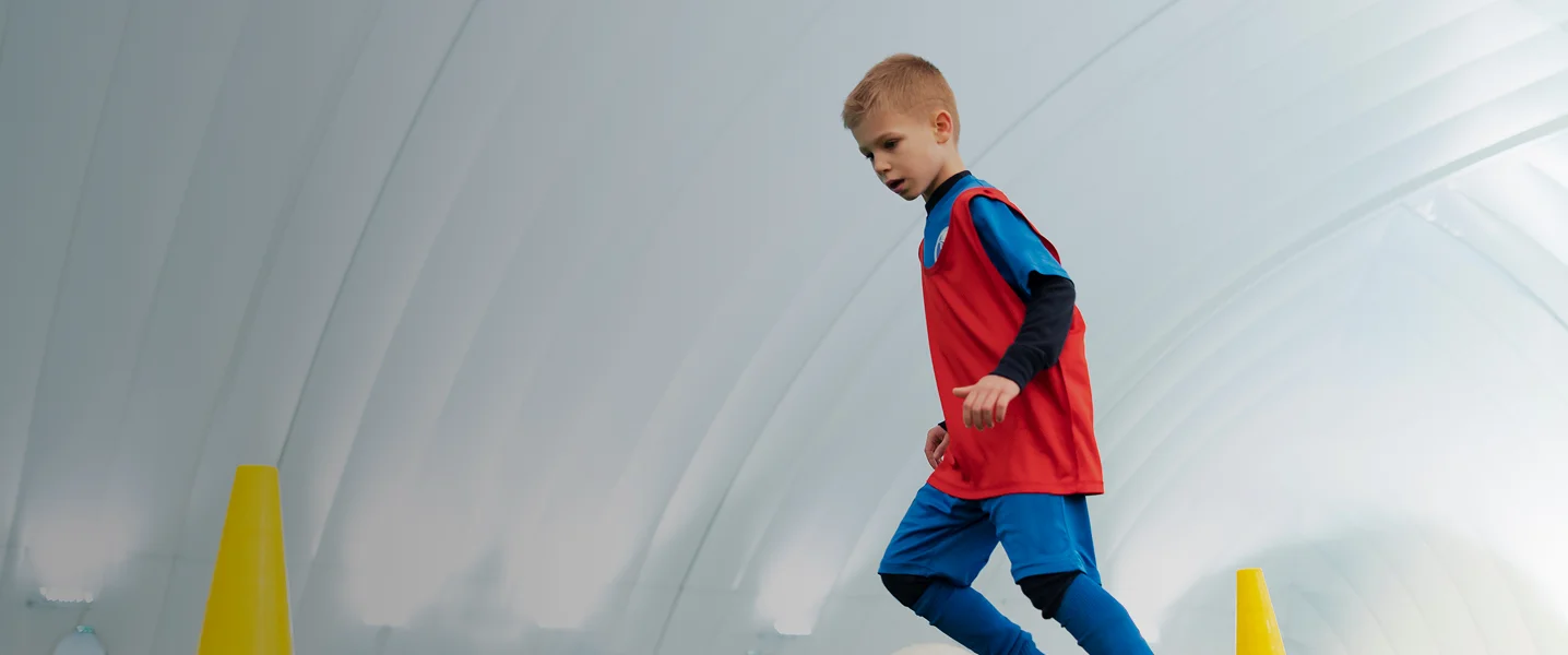 Children's Sports League: Educational and Safe Sport Classes Excited children playing football outdoors, building coordination and teamwork skills.